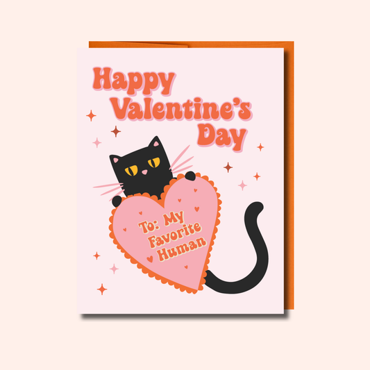 Celebrate love with the Ghost Poppy “My Favorite Human – Valentine’s Day Card.” This charming A2-sized greeting card features an adorable black cat holding a big heart that reads “To: My Favorite Human,” set against a pink, sparkly background with “Happy Valentines Day” at the top. Printed on quality cardstock and blank inside, it’s perfect for adding your own heartfelt message.