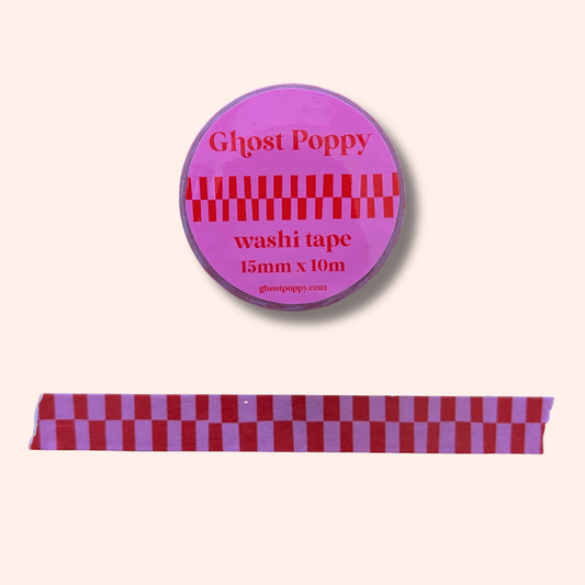 A roll of Ghost Poppy’s Red & Pink Checkerboard Washi Tape features a bold red and pink checkered pattern. Below, a strip of the washi tape showcases the same striking checkerboard design.