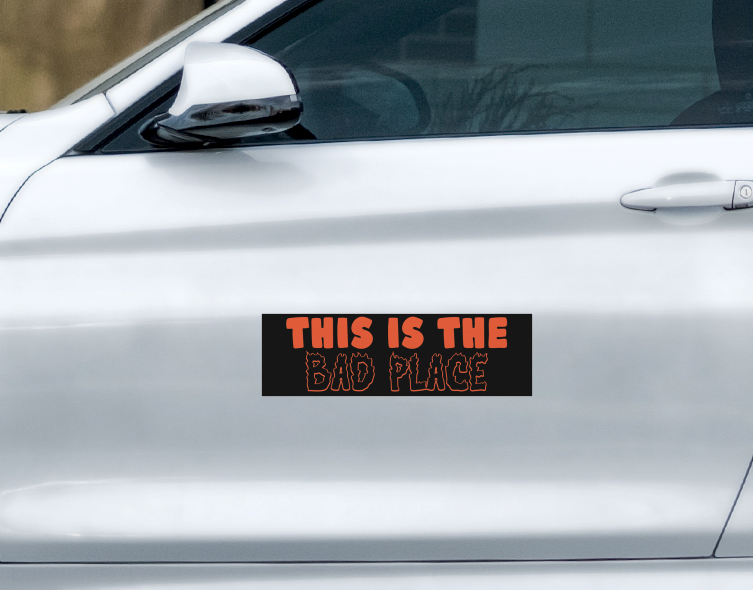 A Ghost Poppy This Is The Bad Place car magnet on a white car door, featuring orange, jagged, flame-style lettering.